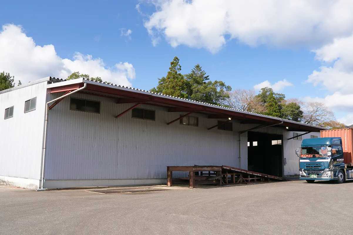 倉庫とその前に停車したトラックの外観