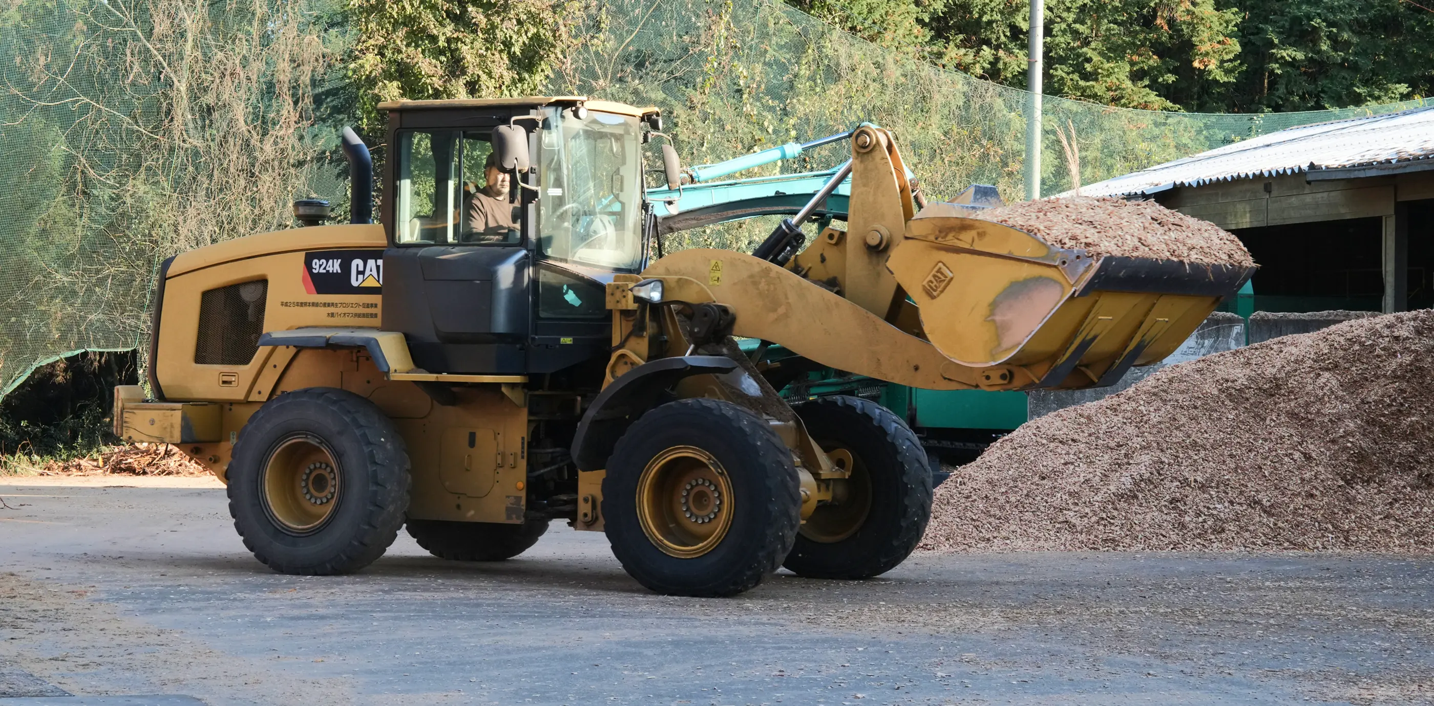 Caterpillar製の重機が木材チップを運搬している様子